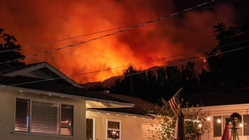 A fire burns behind a residential area.